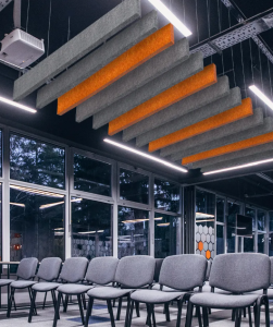 Grey and Orange acoustic Fabric panels are suspended over a conference area with empty seats.