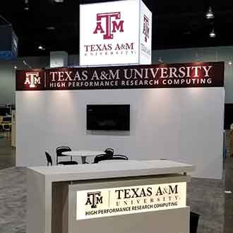 Texas A&M University trade show display with illuminated white cube with the TAMU logo.