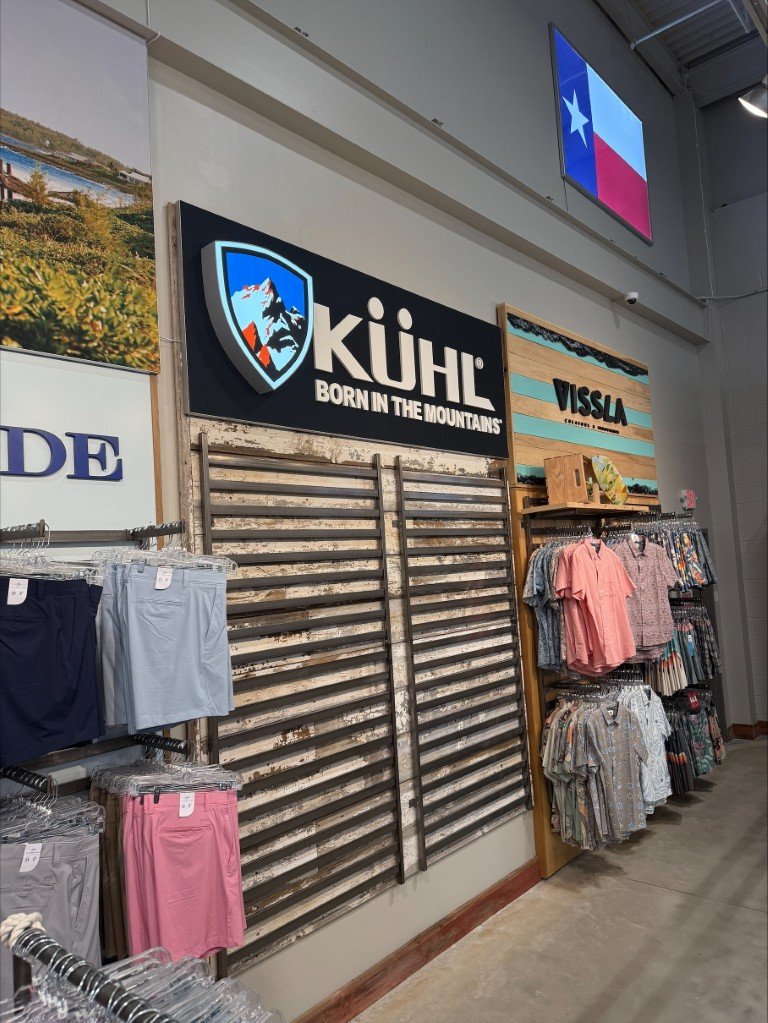 Dimensional wall sign with a shield that is illuminated as a lightbox. This sign represents the Kuhl clothing brand.